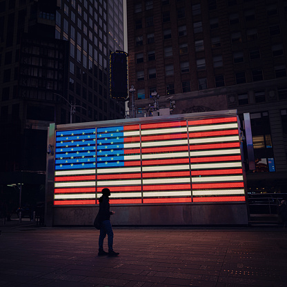 Unrecognizable person silhouette in front of Neon American Flag in Times Square