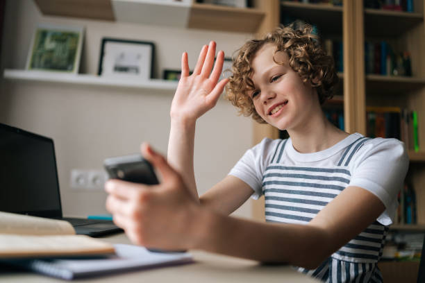 istock Joyful curly girl holding and using mobile phone greeting wave hand , browsing social network apps, surfing internet and scrolling news feed 1438201512