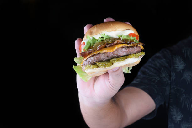 istock beef burger sandwich with bacon cheese salad and soft egg bun, side view on wooden table isolated on black background 1438203667