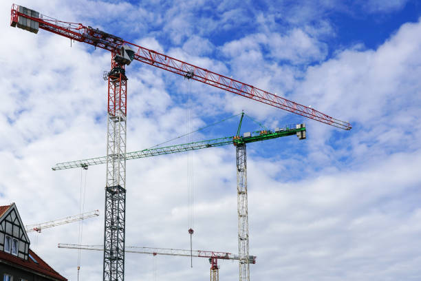 istock Several construction tower cranes at city construction sites against a cloudy sky background 1438204025