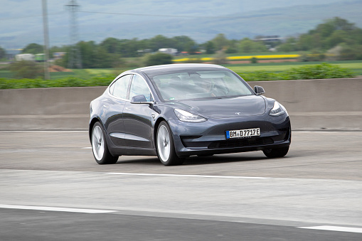 Diedenbergen, Germany - May 12, 2021: Tesla Model 3 on a highway nearby Wiesbaden in Germany. The Tesla Model 3 is an electric four-door fastback mid-size sedan developed by Tesla. Tesla, Inc. is an electric vehicle and clean energy company based in California.