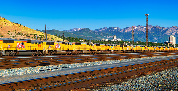 Salt Lake City, Utah, USA - June 11, 2022 : Large number of Union Pacific diesel locomotives with american flags lined up in Salt Lake City with Utah State Capitol in the background.