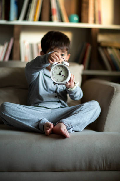 Joyful little boy with showing an alarm clock