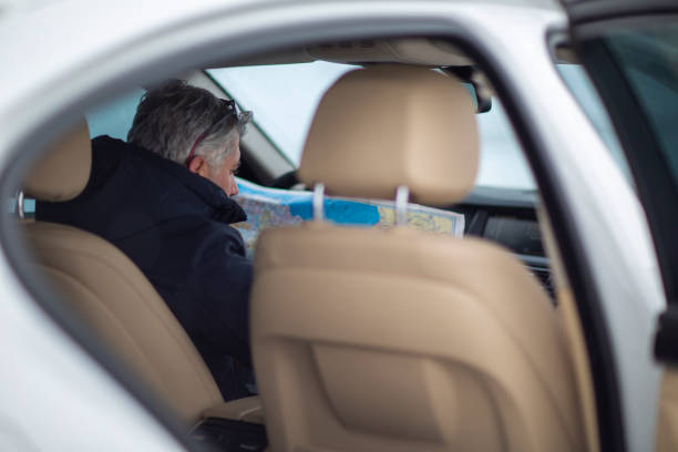Young Man driver in car pointing in to the map