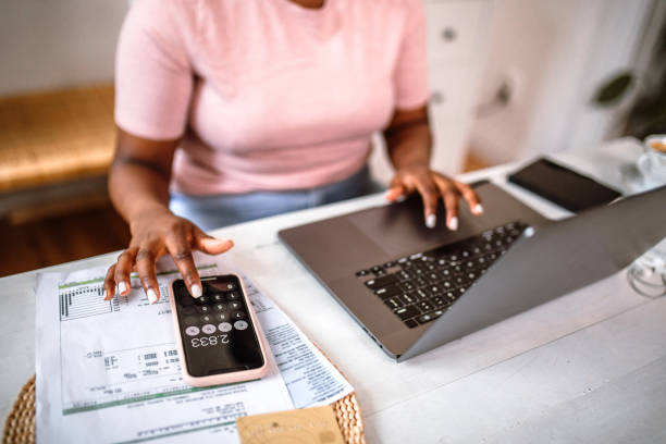 woman managing home finances - calculator imagens e fotografias de stock