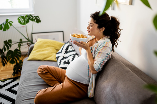 Young pregnant woman craving for food at home