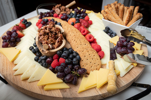 Various cheese, crackers, berries and nuts on a fine charcuterie board
