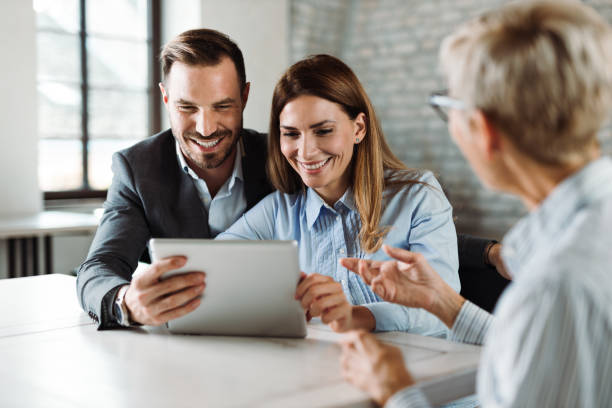 istock Happy couple using digital tablet on a meeting with insurance agent 1438211223