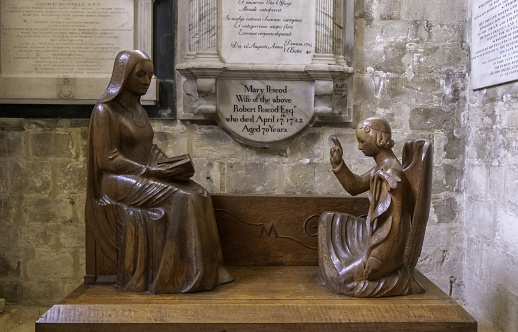 Winchester, United Kingdom – December 01, 2018: A wood carving of a kneeling angel in front of a seated figure in Winchester Cathedral