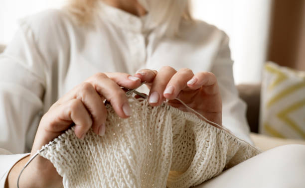 istock Woman's hands knitting white wool yarn pattern. Closeup horizontal photo. 1438212007