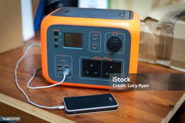 Portable Power Station Solar Electricity Generator With Mobile Phone Plugged In To Charge Stock Photo - Download Image Now
