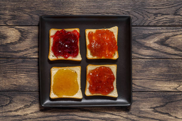 istock Toasted bread with different jams on square black plate on table above 1438212159