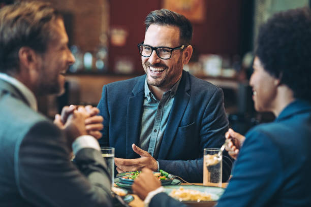 istock Smiling businessman talking to his coworkers during a dinner 1438213576