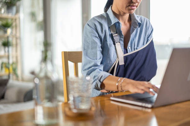 woman working on laptop - arm sling imagens e fotografias de stock