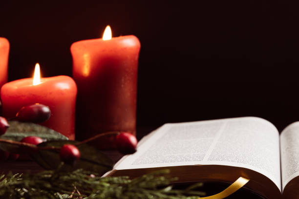 istock Open bible and red candles on black background 1438218505