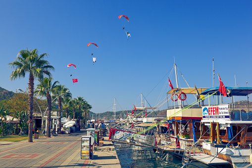 Fethiye/Mugla, Turkey - October 21, 2021: pilots of Turkish Aeronautics Association fly paragliders over Fethiye marina. 21st International Fethiye Oludeniz Air Games Festival