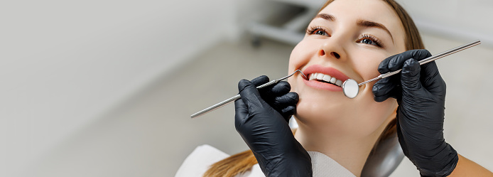 Banner for dental theme. Close-up of smiling woman with white teeth during medical examination. Concept of tooth whitening, treatment, veneers, professional clinic. Photo with empty copy space