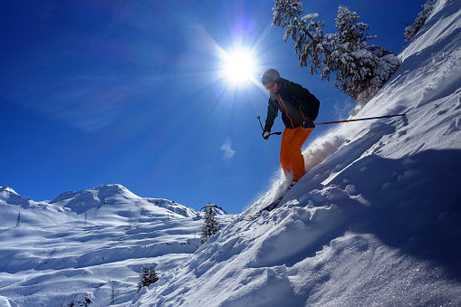 Male skier riding in the deep snow on a sunny day in the skiresort of St. Anton am Arlberg in Tirol, Austria