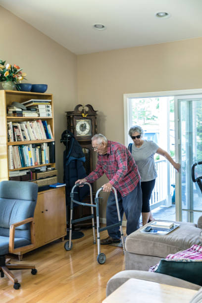 Impatient Elderly Old Man Arriving Home Arriving back home after a gentle exercise visit to a local public nature park with his senior adult woman home caregiver daughter, an elderly, now very grumpy old man senior adult is in a hurry to sit down and relax. His daughter closes the door behind them as he pushes his orthopedic walker impatiently into his attached in-law apartment. Some blurred motion. walking into glass door stock pictures, royalty-free photos & images