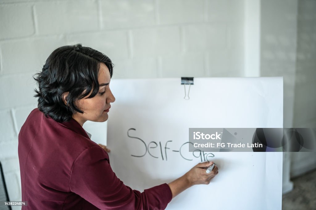 Mid adult psychotherapist woman writing about self -care on a whiteboard 30-34 Years Stock Photo