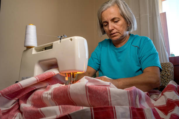 White-haired woman sewing with machine at home