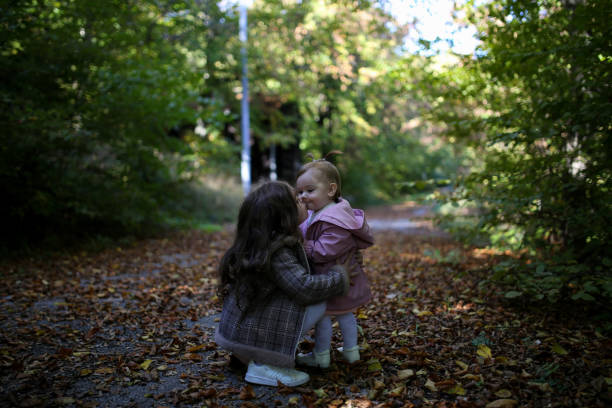deux petites sœurs drôles s’amusent lors d’une randonnée en forêt sur une belle photo d’automne - footpath european alps fence woods photos et images de collection