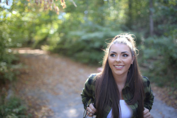 Young woman walking through forest. She exploring forest and enjoy in autumn day