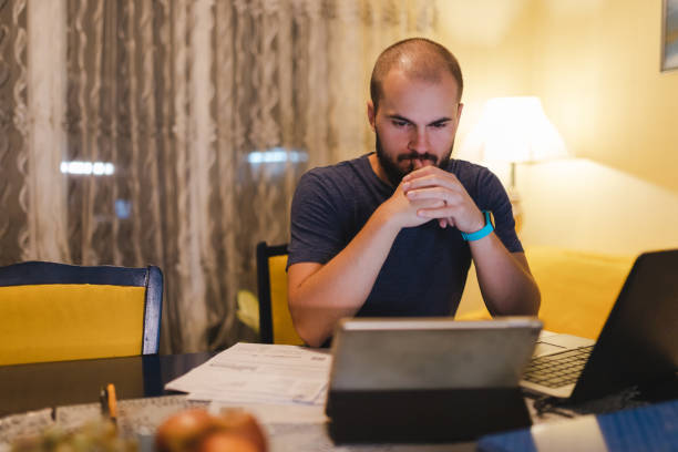 istock Young man going through his bills at home, looking worried 1438231451