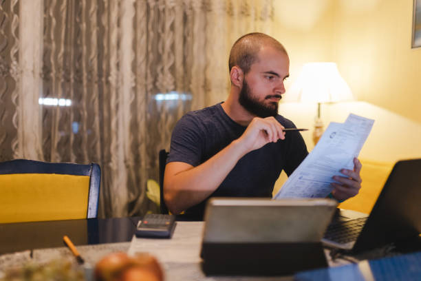 istock Bald young man going through his bills at home 1438231460