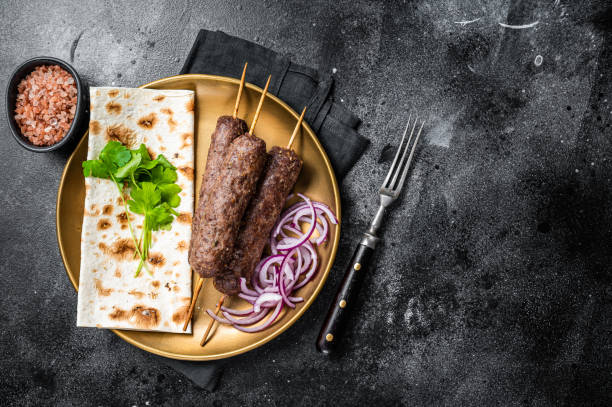 istock Lamb meat kofta kebab, onion and flat bread on plate. Black background. Top view. Copy space 1438231505