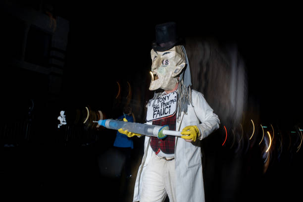 Parader dressed as Dr. Fauci holds a giant syringe protesting vaccines at the annual 6th Ave Halloween Parade in NYC