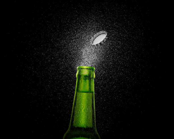 foto in primo piano di una bottiglia di birra verde che spruzza gocce di birra su uno sfondo nero. tappo di birra che vola sopra la bottiglia. rendering 3d - beer bottle beer bottle bottle cap foto e immagini stock