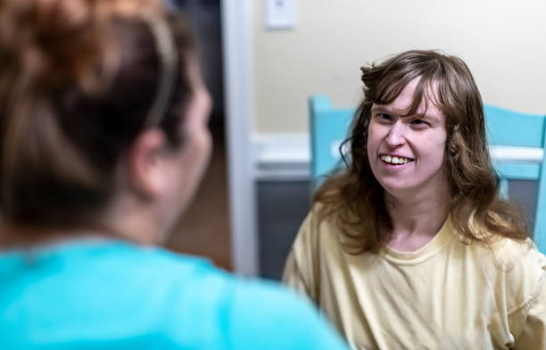 Caregiver brings a smile to intellectually disabled woman's face - fotografia de stock