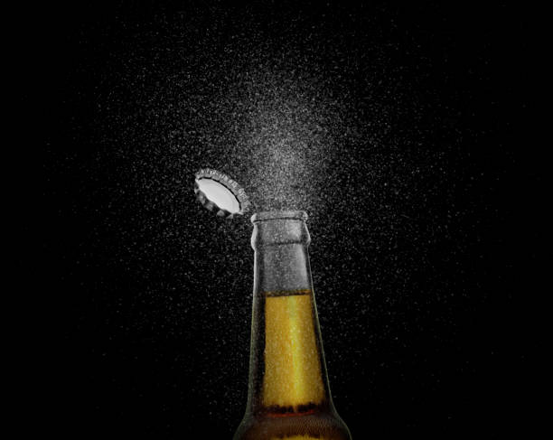 foto in primo piano di una bottiglia di birra marrone che spruzza gocce di birra su uno sfondo nero. tappo di birra che vola sopra la bottiglia. rendering 3d - beer bottle beer bottle bottle cap foto e immagini stock