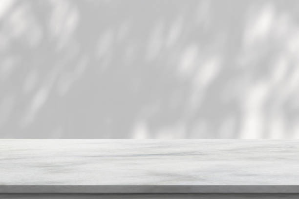 istock Marble table with tree shadow drop on white wall background for mockup product display 1438257301