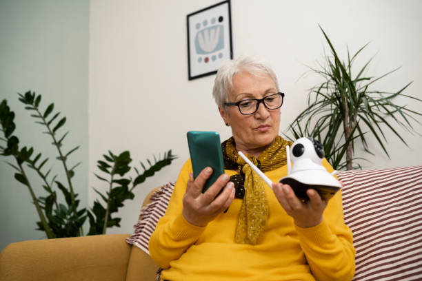 istock Happy senior woman using a mobile app to adjust her smart camera 1438257365
