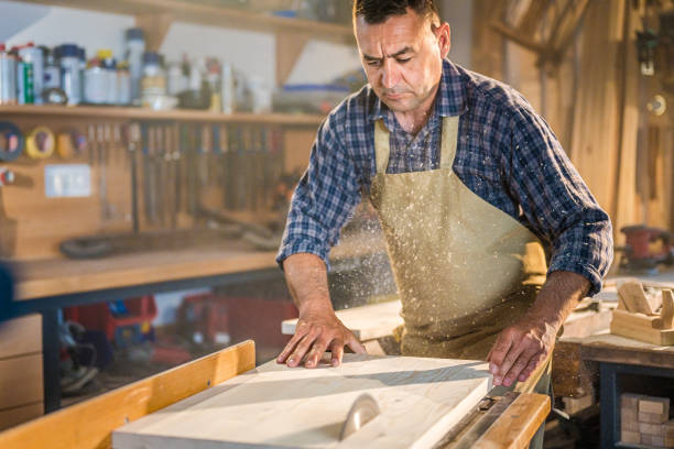 istock Concentrated worker cutting wooden board on circular saw 1438257455