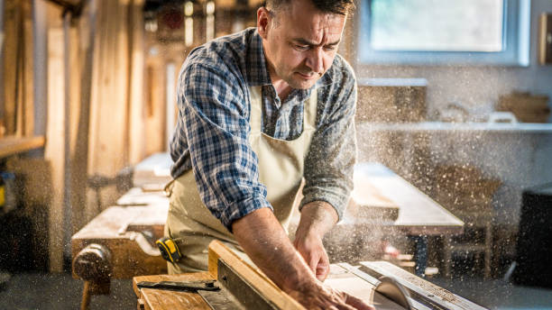 istock Experienced carpenter sawing wooden material on circular saw 1438257461