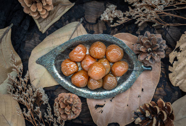 istock Three flavored preserved chinese plums (Preserved fruits) on small silver leaf shaped plate. 1438258873