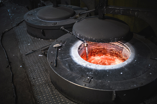 Molten metal and bronze are poured into mold by melter in a foundry plant.