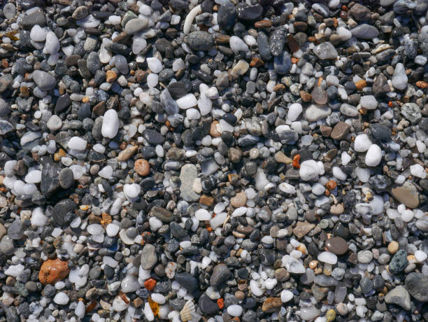 istock Mediterranean beach, sand and stones texture. Grey and black pebbles background. 1438262428