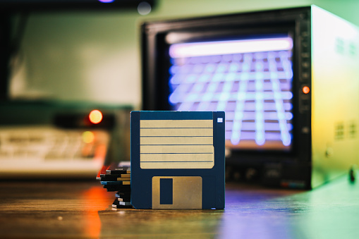 80s technology in use today, floppy disks and a CRT monitor displaying synth wave music visuals.