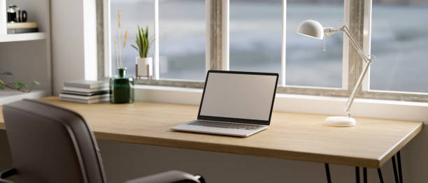 Minimal Scandinavian home workspace with laptop mockup on wood table against the window stock photo