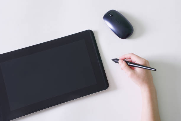 Woman's hand and stylus next to graphics tablet and computer mouse. White background. The concept of modern creativity through digital technology. Copy space. Close-up