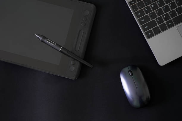 Stylus and graphics tablet with a screen on a black background next to a laptop and a computer mouse. The concept of modern creativity through digital technology.  Copy space. Close-up