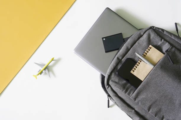 istock Laptop backpack and modern gadgets: laptop, external ssd, smartphone, notepad and pen. Next to toy plane on a yellow and white. Luggage for air travel. Problem of issuing international visas. 1438270763