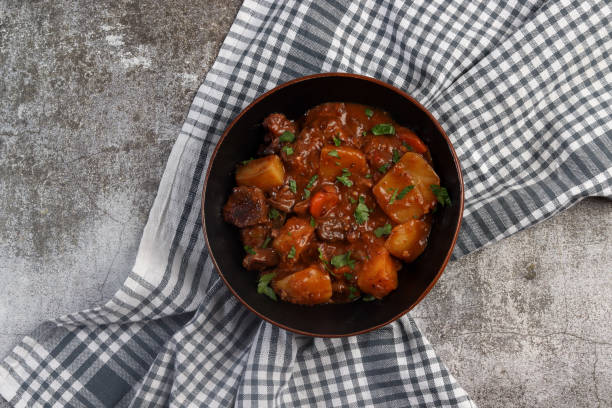 istock Rustic Beef Stew with Carrots & Potatoes in a bowl on a dark background. Top view, flat lay 1438272779