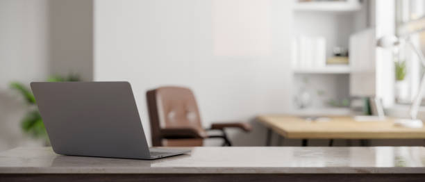 istock Modern office tabletop with laptop and copy space over blurred modern office in the background. 1438274269