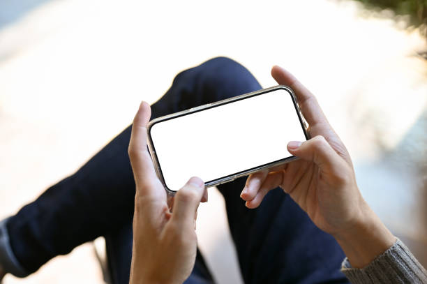 istock A smartphone white screen mockup in a horizontal position is in a male's hands. 1438274470