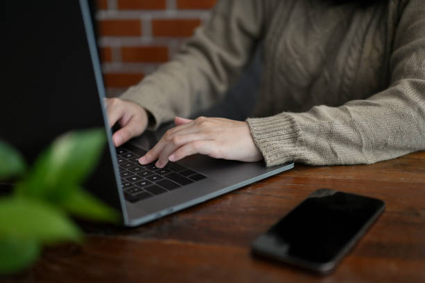 istock Female remote working at the coffee shop, using laptop, typing on keyboard. cropped image 1438277856